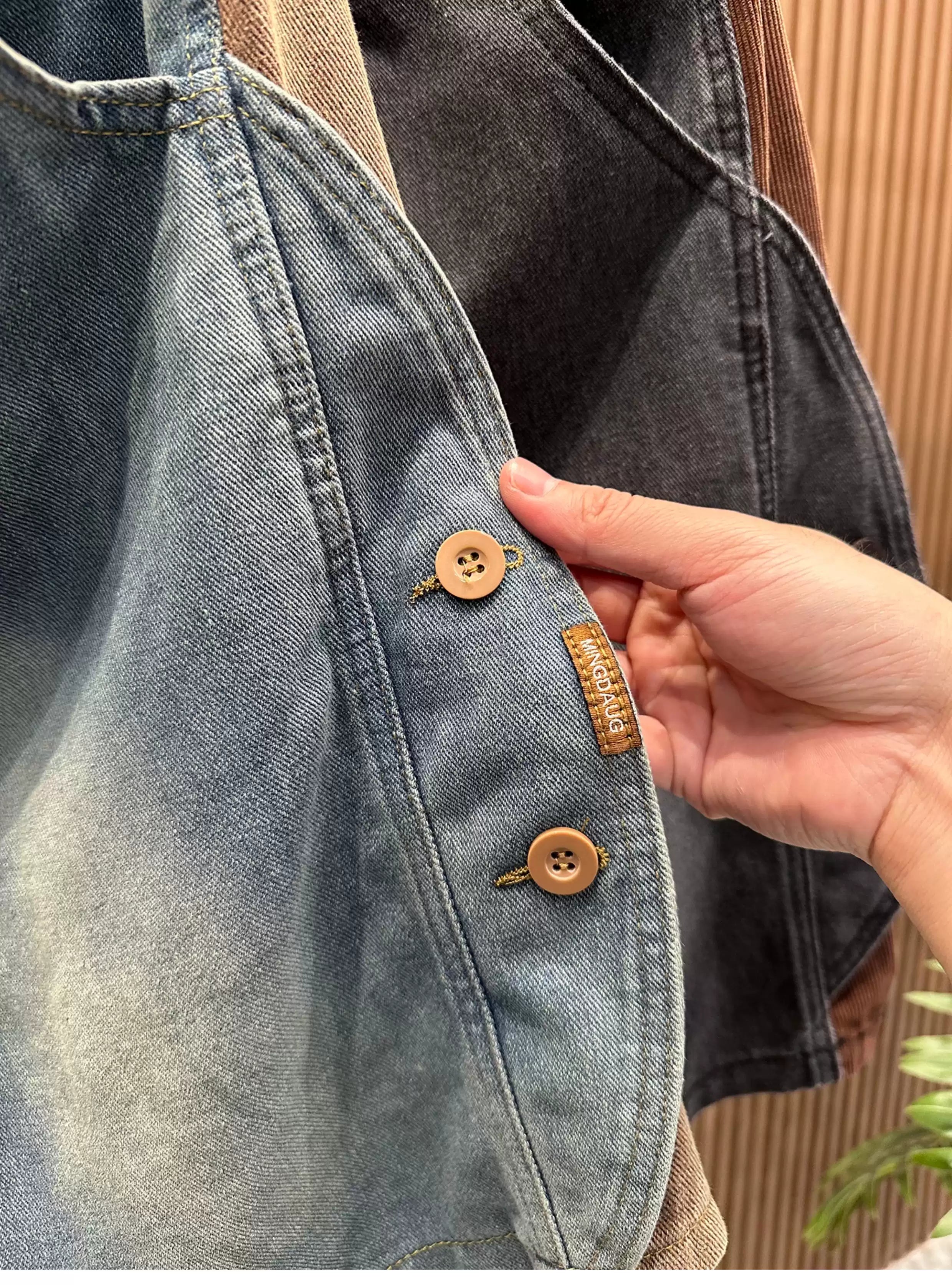 Close-up view of the Common Theory Vintage Panel Denim Shorts, highlighting a hand touching the contrast brown corduroy side paneling and the unique side button detailing on the washed blue denim.