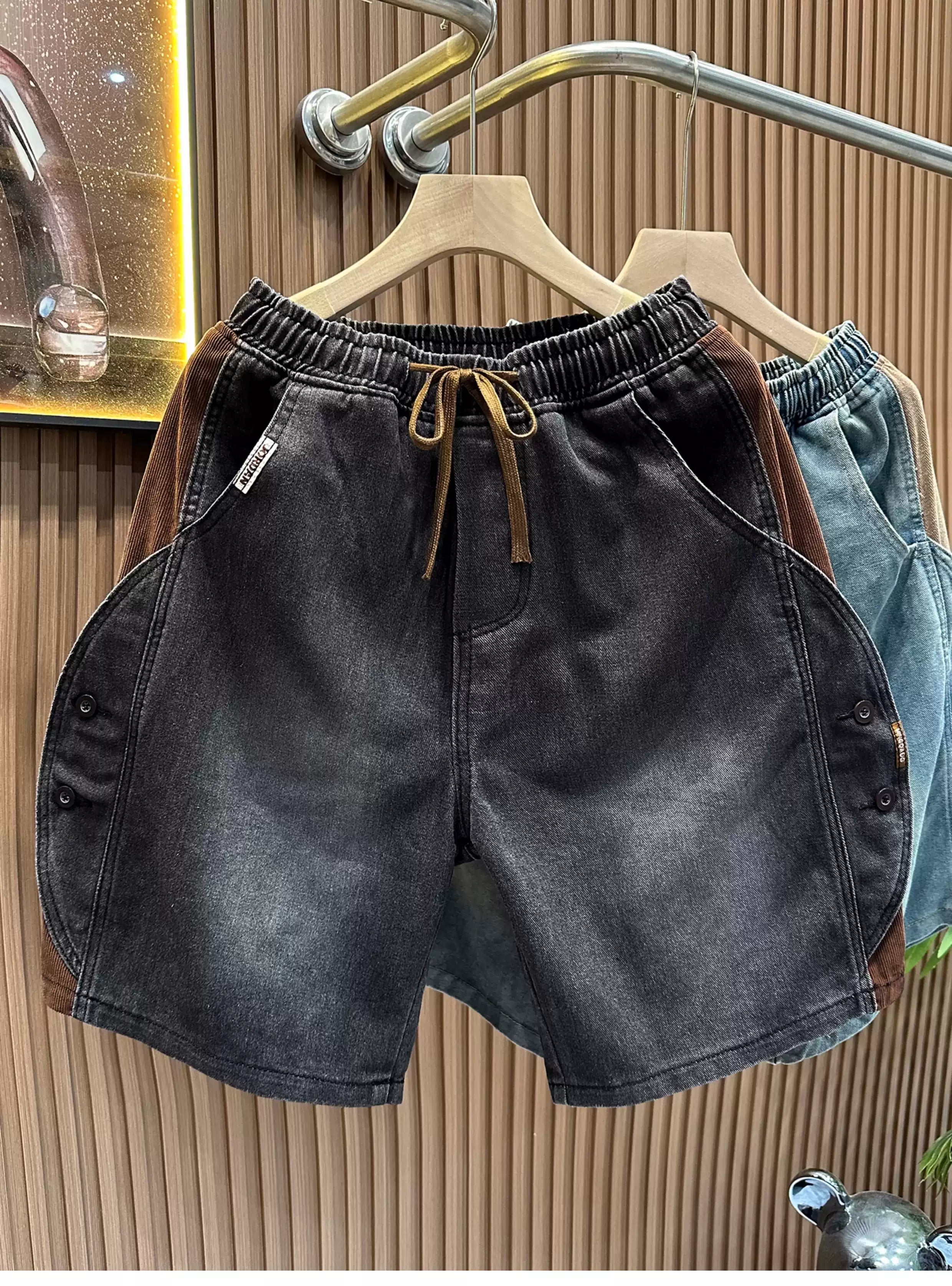 Front view of the Common Theory Vintage Panel Denim Shorts in dark vintage grey, highlighting their relaxed oversized fit, elastic waistband with drawstrings, and unique paneled side button detailing.