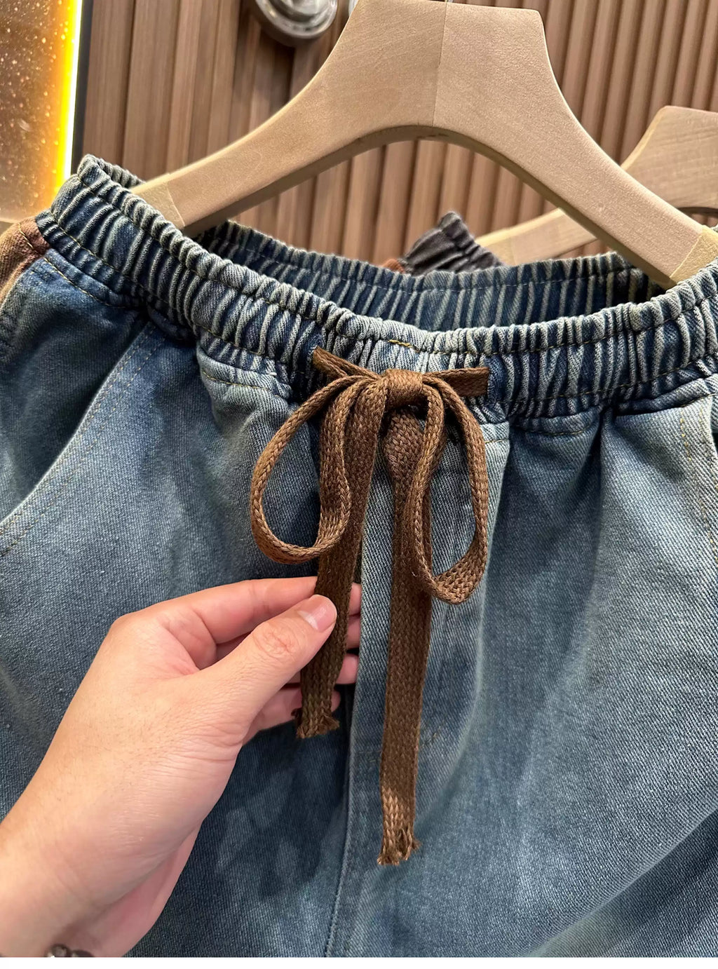 Front view of the Common Theory Vintage Panel Denim Shorts in dark vintage grey, showcasing the relaxed oversized fit, elastic waistband with drawstrings, and unique paneled side button detailing.